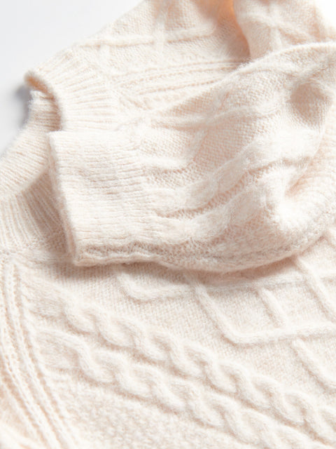 Close-up of a cream-colored knitted sweater with cable pattern
