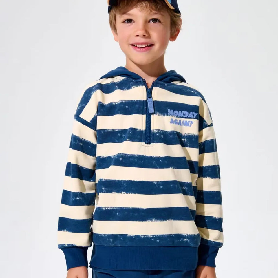 A young boy wearing a navy blue and cream horizontally striped hoodie with a distressed texture, featuring the text 'MONDAY AGAIN!' on the chest, set against a plain light gray background.