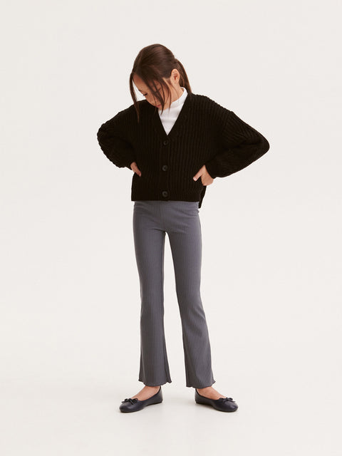 Person wearing a black cardigan, white shirt, gray pants, and black shoes on a white background