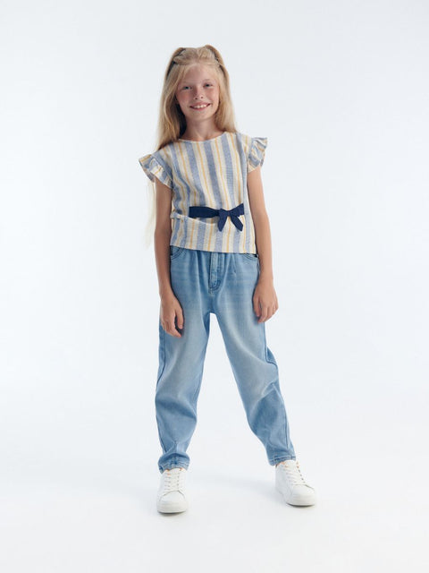 Young girl wearing a striped top and denim pants on a white background