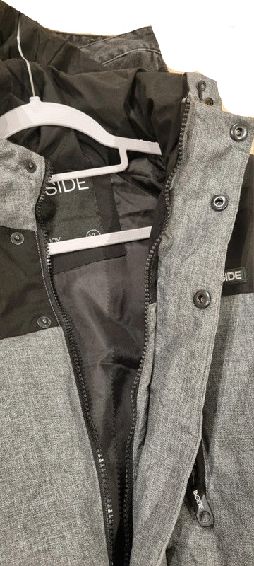 Gray jacket with black lining on a hanger against a wooden floor background