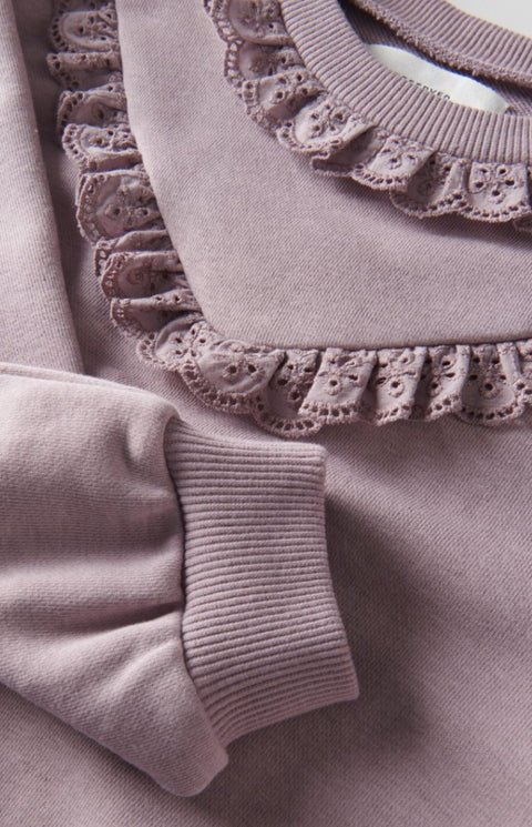 Close-up of a textured fabric with ruffled trim in a soft pink color.