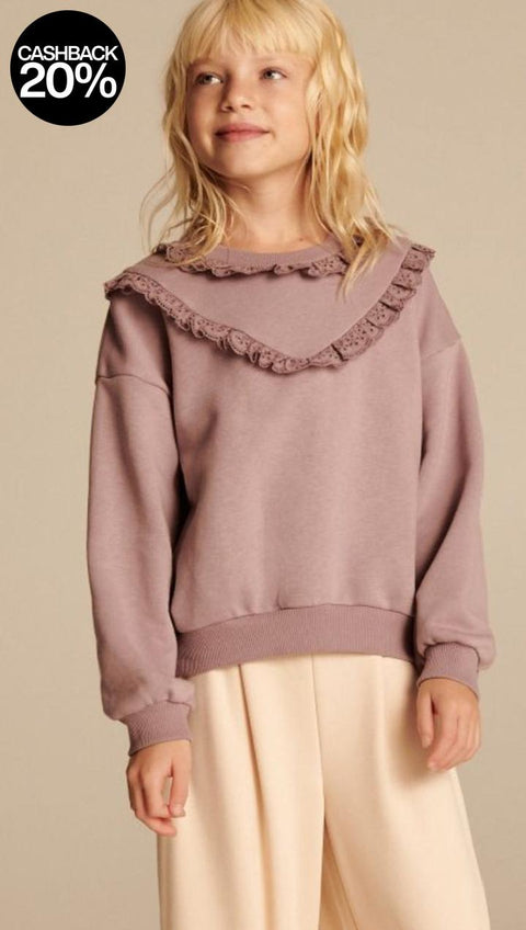 Young girl wearing a mauve sweater with ruffled collar against a beige background