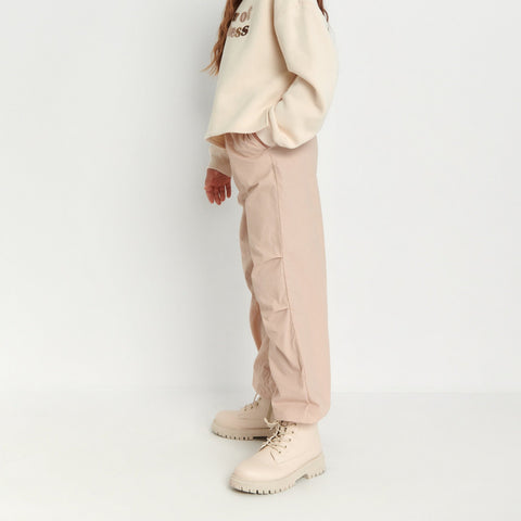 Person wearing a beige sweater and cargo pants on a white background