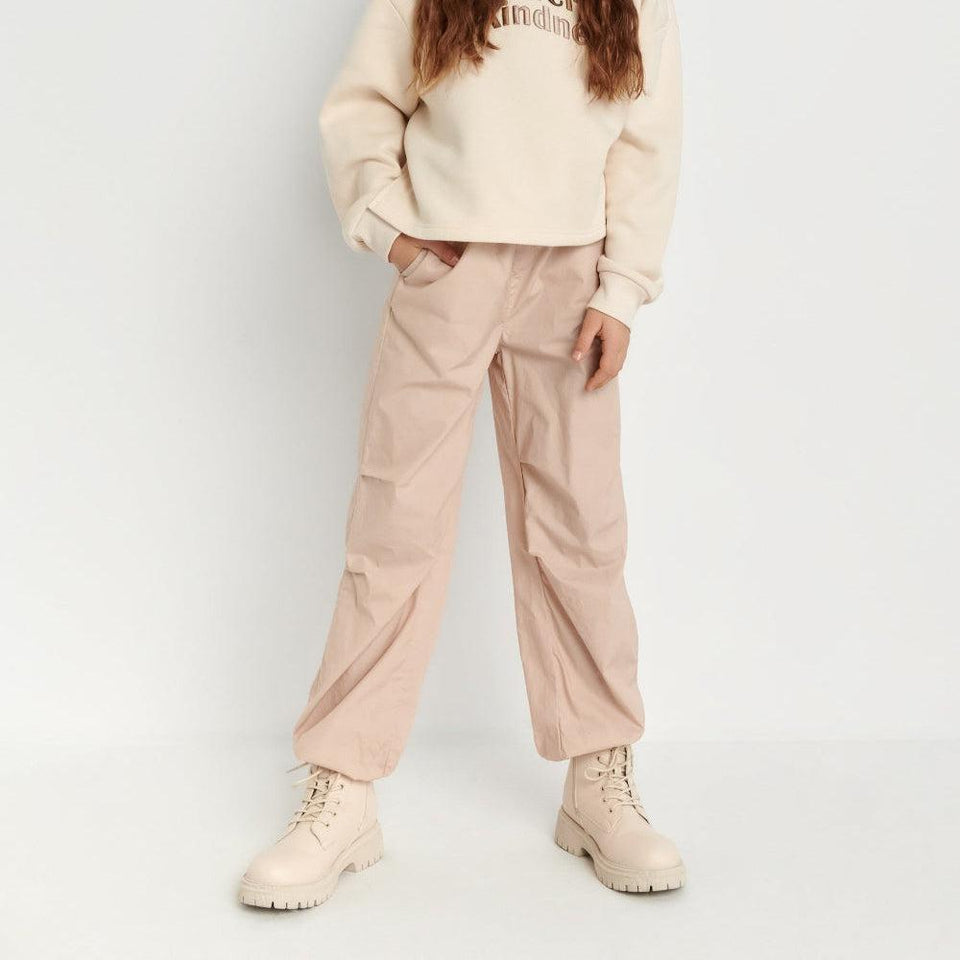 Person wearing a beige sweater and pants on a white background