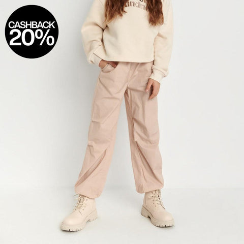 Person wearing a beige sweater and pants on a white background