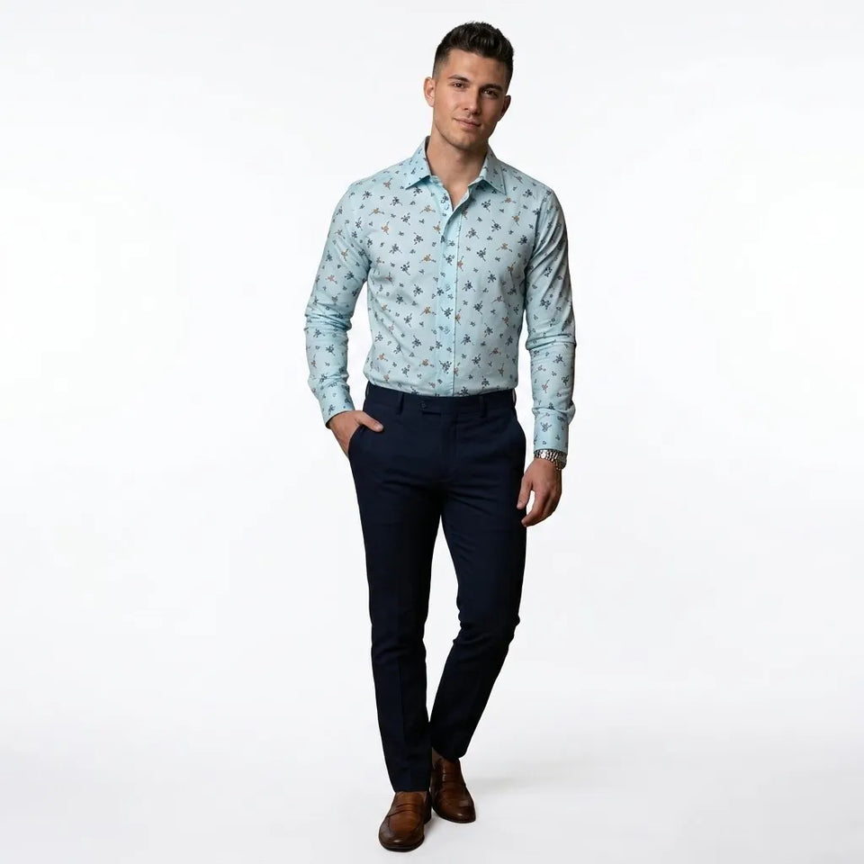 A man modeling a light blue long-sleeve button-down shirt with a small floral pattern, paired with dark navy trousers and brown leather shoes, against a plain white studio background.