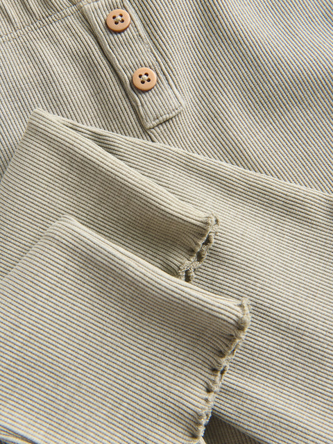 Close-up of a folded corduroy fabric with buttons on a matching fabric background.