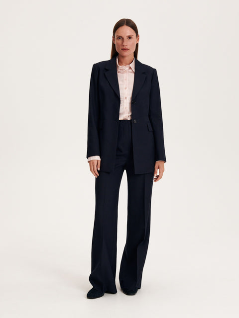 Person wearing a navy suit with a white shirt on a white background