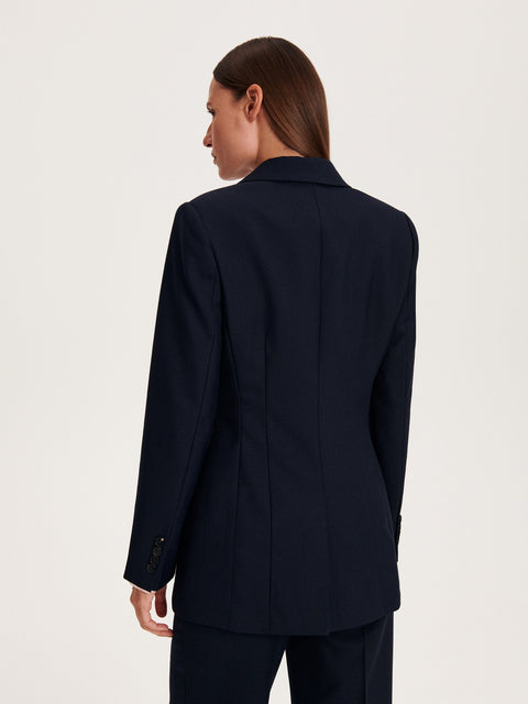 Person wearing a navy blazer on a light gray background