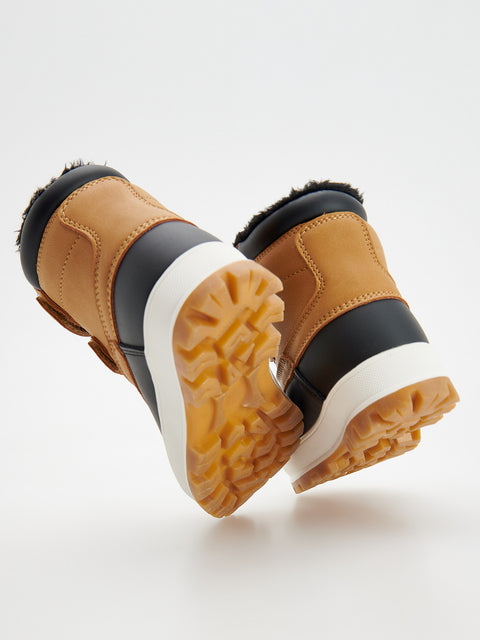 Pair of brown and black winter boots with white soles on a light gray background