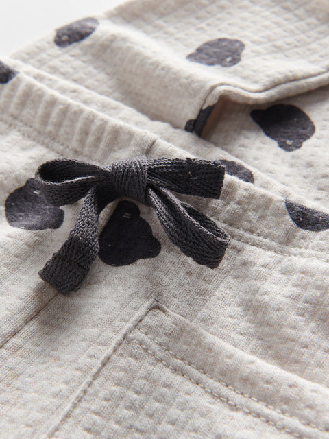Close-up of a textured fabric with a black bow and patterned background