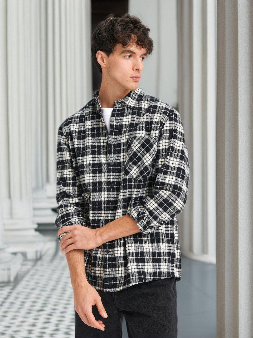 Person wearing a black and white plaid shirt standing against a neutral background