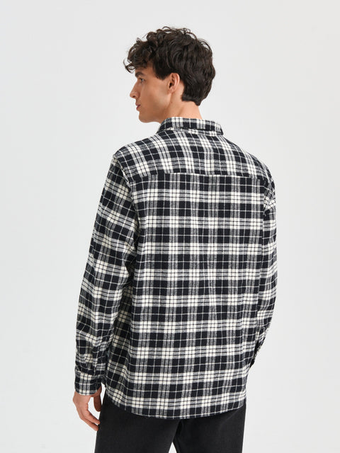 Person wearing a black and white plaid shirt on a light gray background