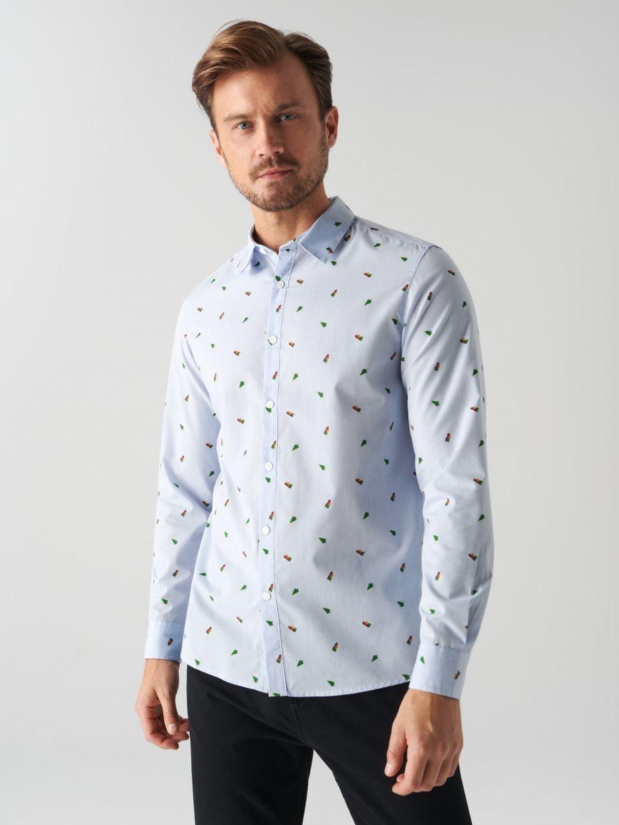 Man wearing a light blue shirt with a subtle pattern on a plain background