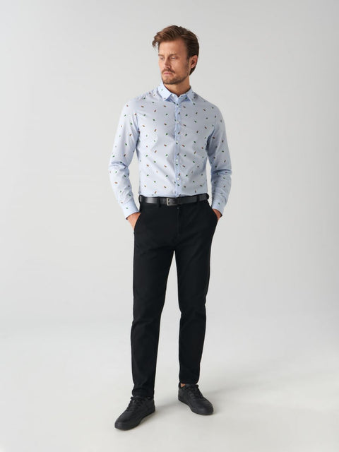 Man wearing a light blue patterned shirt and black pants on a white background