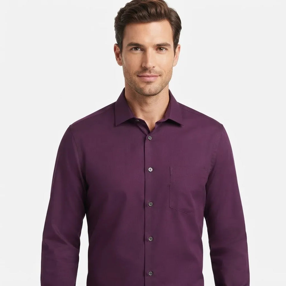 A man wearing a long-sleeve button-down shirt in a solid deep purple color, shown from the chest up against a light gray studio background.