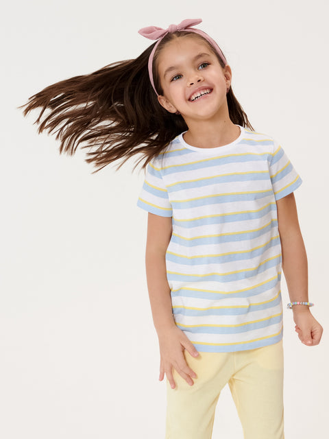 Young girl wearing a striped shirt and yellow pants with a pink headband on a white background