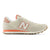 A New Balance sneaker in light beige with a coral orange accent stripe, white 'N' logo, and a brown gum outsole, shown from a side profile on a white background.