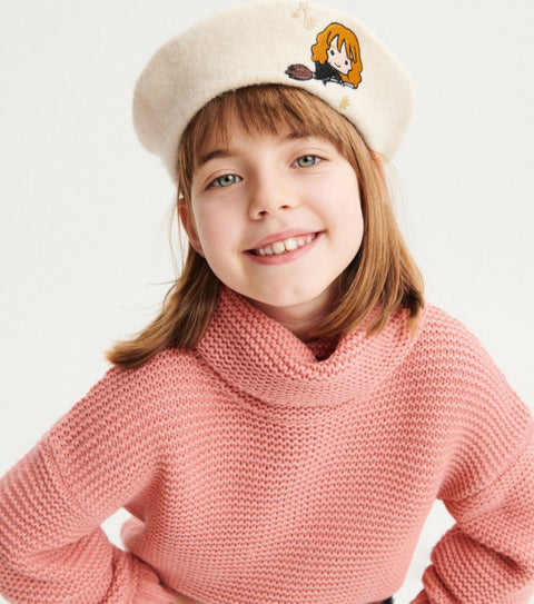 Young girl wearing a pink sweater and beige beret with a cartoon character on a white background