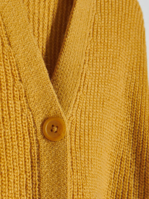 Close-up of a mustard yellow knitted cardigan with a button.