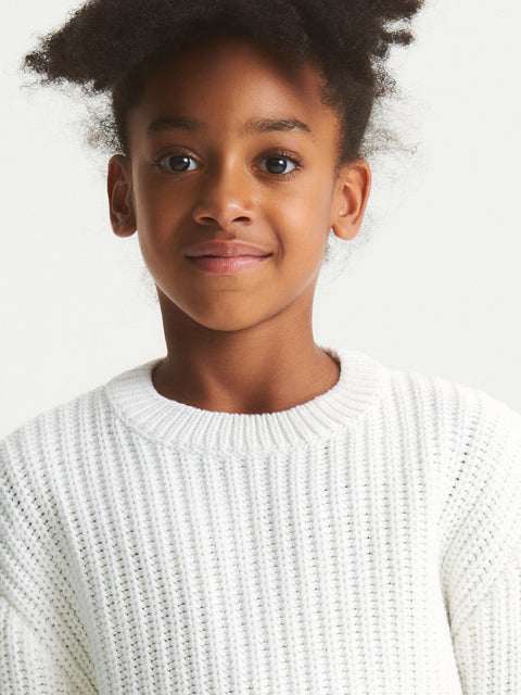 Child wearing a white sweater against a plain background