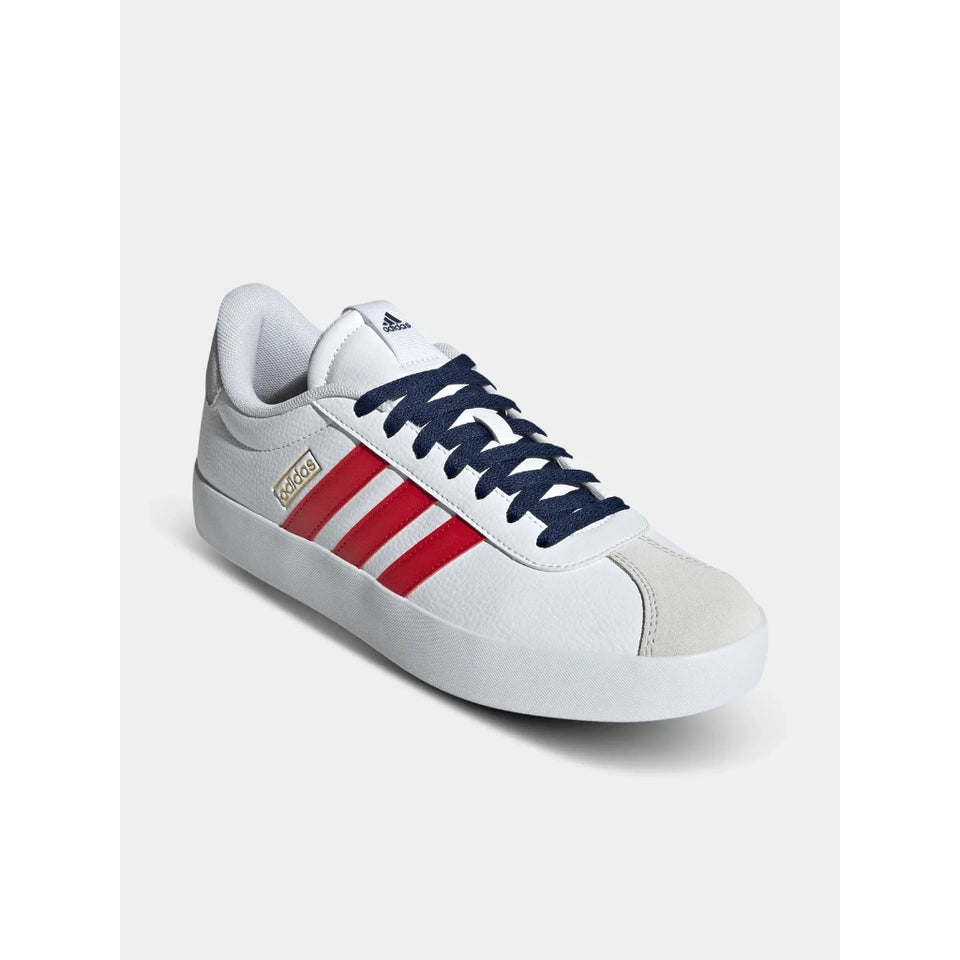 A white Adidas sneaker featuring navy blue laces, red three-stripes on the side, a gold logo accent, and a white rubber sole, shown against a light gray background.