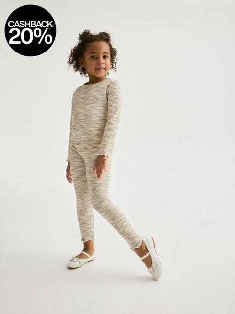 Child wearing a beige long-sleeve top and leggings on a white background