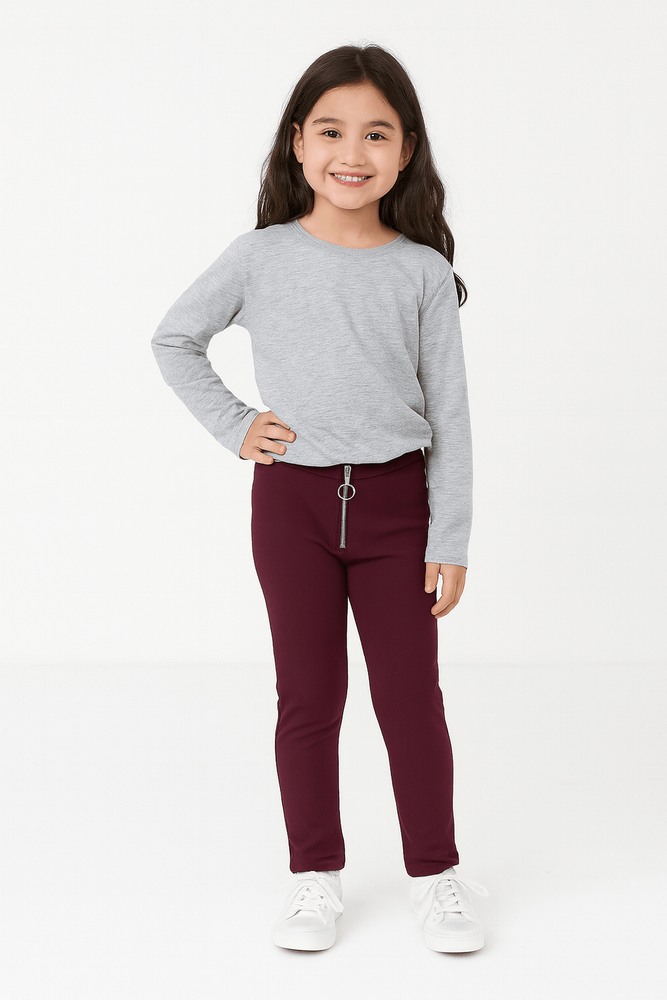 Young girl wearing a gray long-sleeve shirt and burgundy pants on a white background