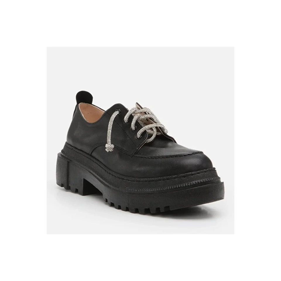 A black leather lace-up shoe with chunky lug soles and silver rhinestone-embellished laces, shown on a light gray background.