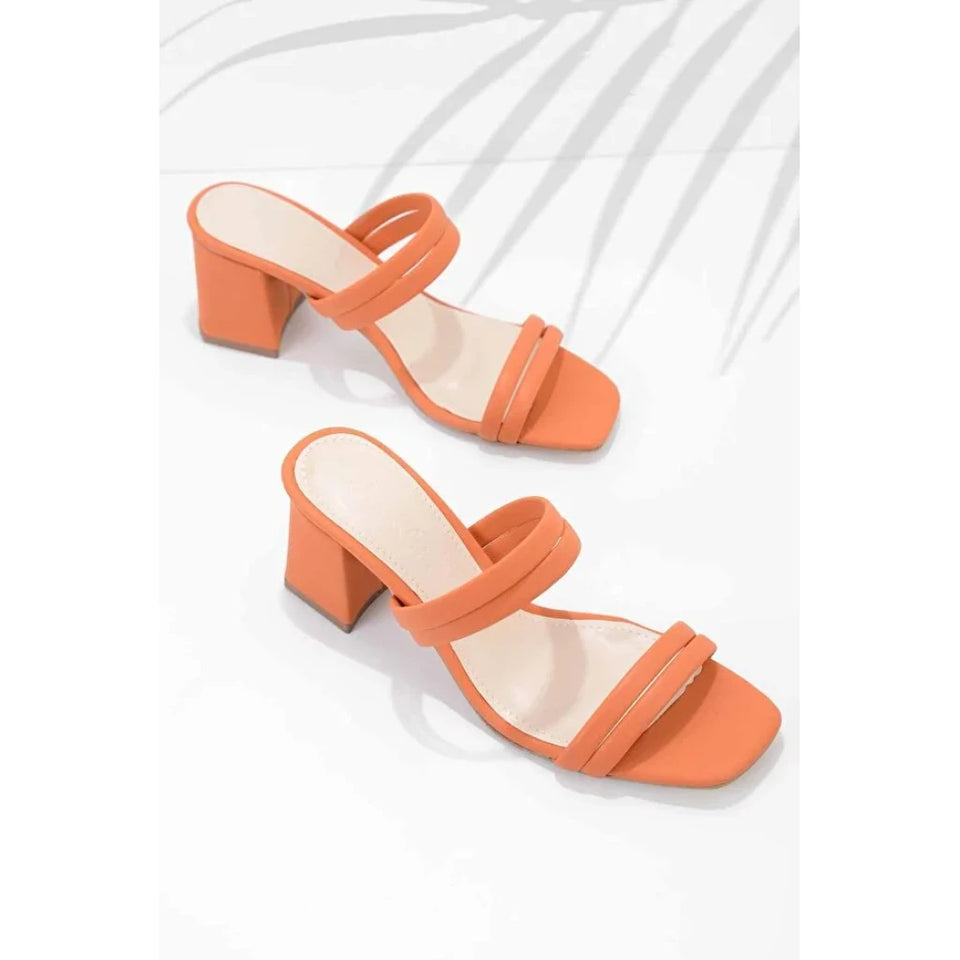A pair of women's heeled mule sandals in a vibrant orange color, featuring a square toe, double front straps, and a chunky block heel, displayed on a clean white background with soft leaf shadows.
