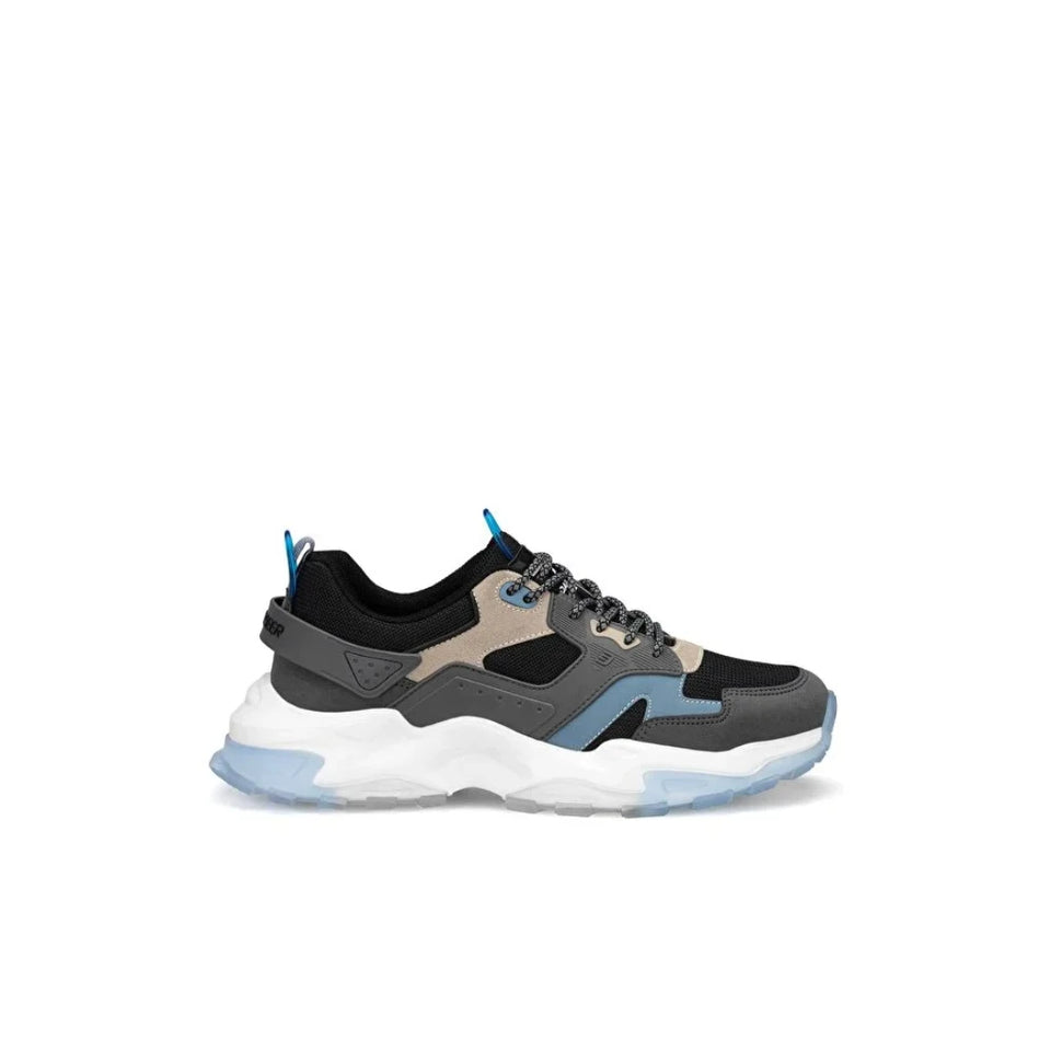 A low-top athletic sneaker shown from the side profile against a plain white background. The shoe features a black and dark gray upper with a beige suede overlay, light blue accents on the laces and side, and a chunky white and light blue sole.
