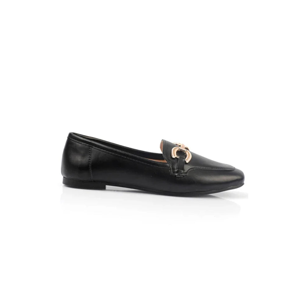 A black leather flat shoe with a gold-tone horsebit detail on the toe, shown in profile against a white background.