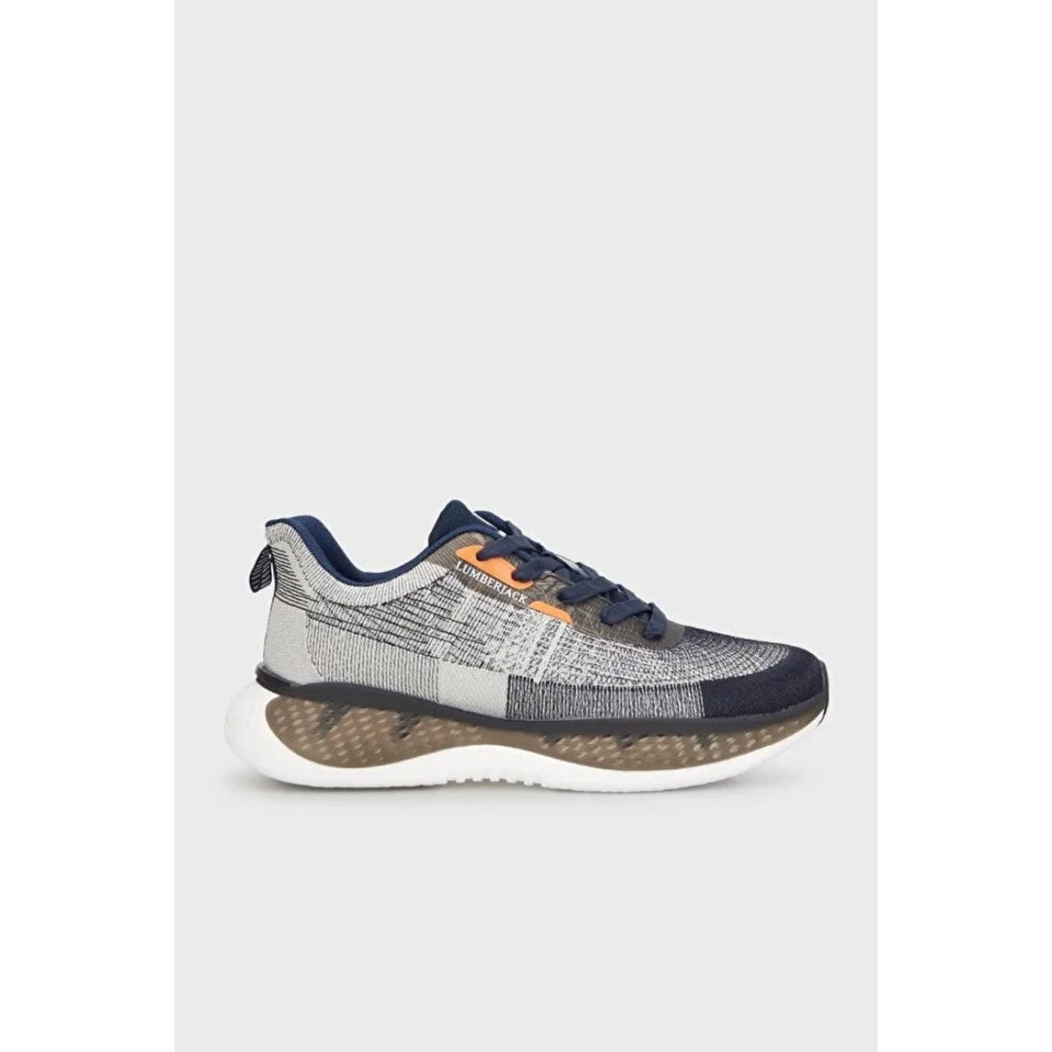 A single athletic sneaker shown in profile against a light gray background. The shoe features a textured knit upper in gray and navy blue, navy laces, a small orange accent near the collar, a white midsole, and a brown and white wavy outsole.