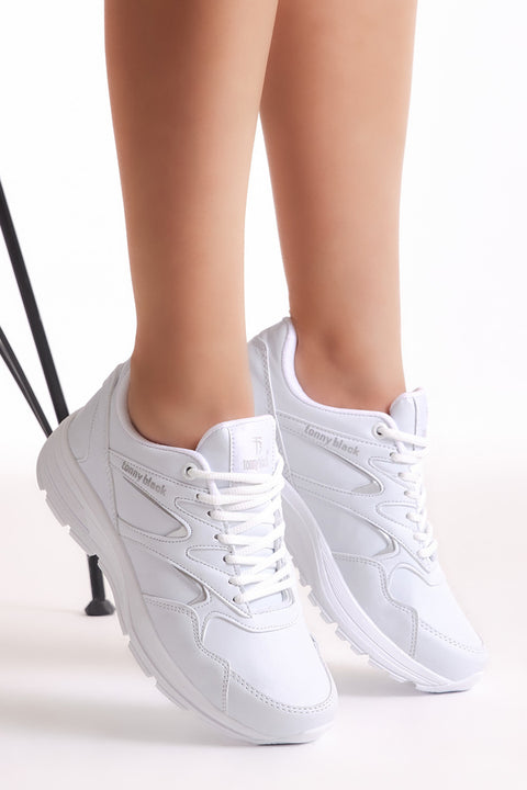 White sneakers worn by a person on a white background
