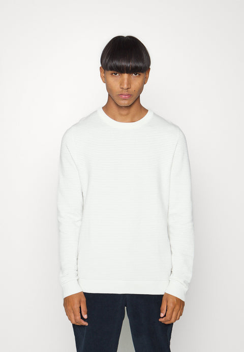 Person wearing a white sweater against a plain background