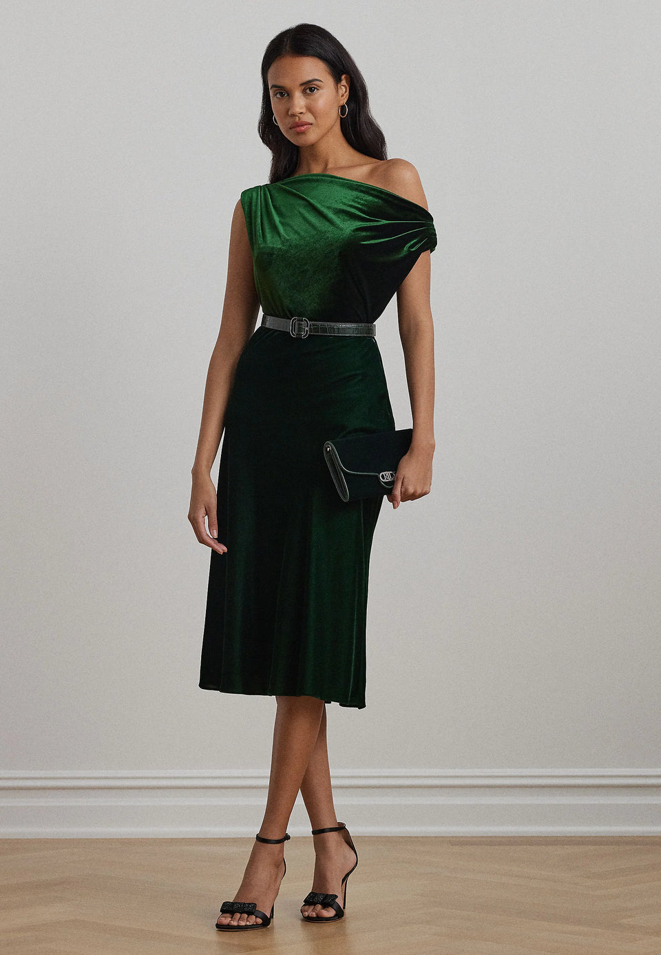 Woman wearing a green off-shoulder dress with a belt against a plain background