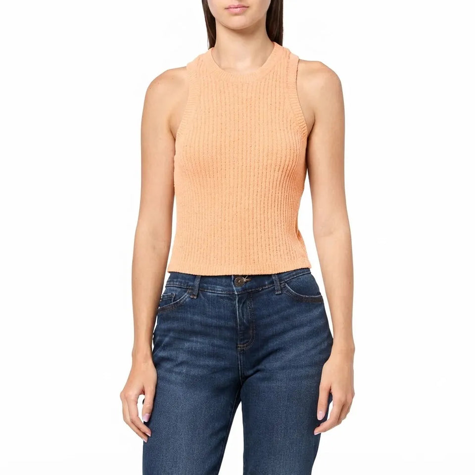 A woman wearing a sleeveless ribbed knit top in a light peach-pink color, paired with dark blue jeans, against a plain white background.
