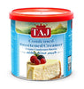 Taj condensed sweetened creamer container with a slice of cheesecake and berries on a white background