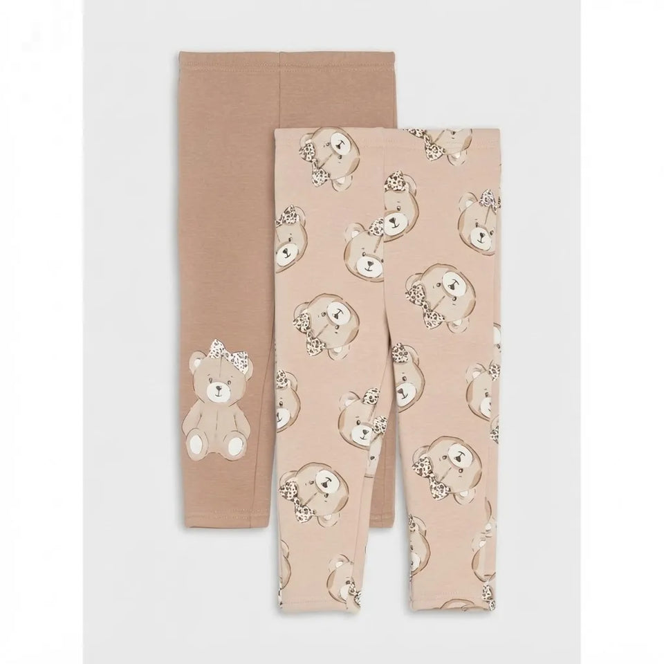 A pair of toddler leggings folded to show two styles: one solid taupe-brown legging and one light blush pink legging with an all-over teddy bear face print and a single teddy bear graphic on the leg.