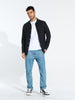 Man wearing a black shirt, white t-shirt, blue jeans, and black sneakers on a white background