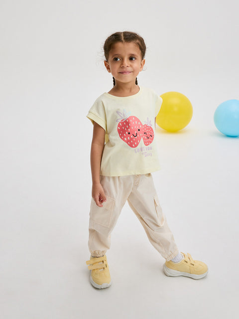 Child wearing a light-colored t-shirt with a design, standing against a plain background
