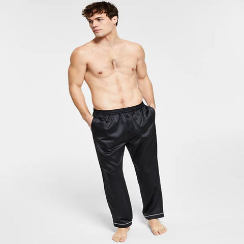 Man wearing black satin pajama pants on a white background