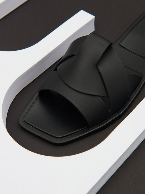 Black sandal on a white platform with a black background