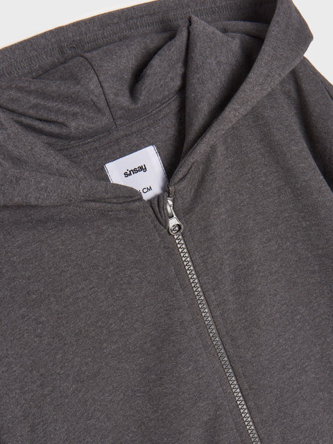 Close-up of a gray hoodie with a zipper and a brand label on a light gray background