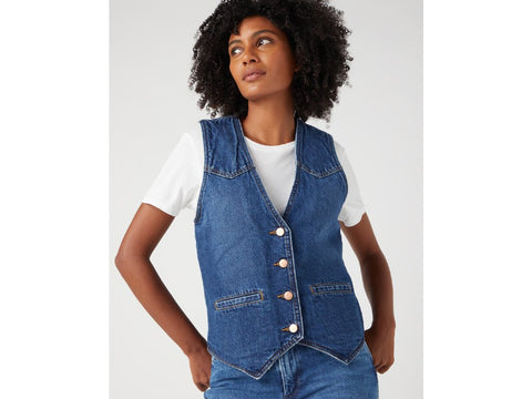 Woman wearing a denim vest over a white shirt on a light gray background