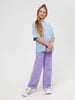 Young girl wearing a light blue shirt and purple pants on a white background