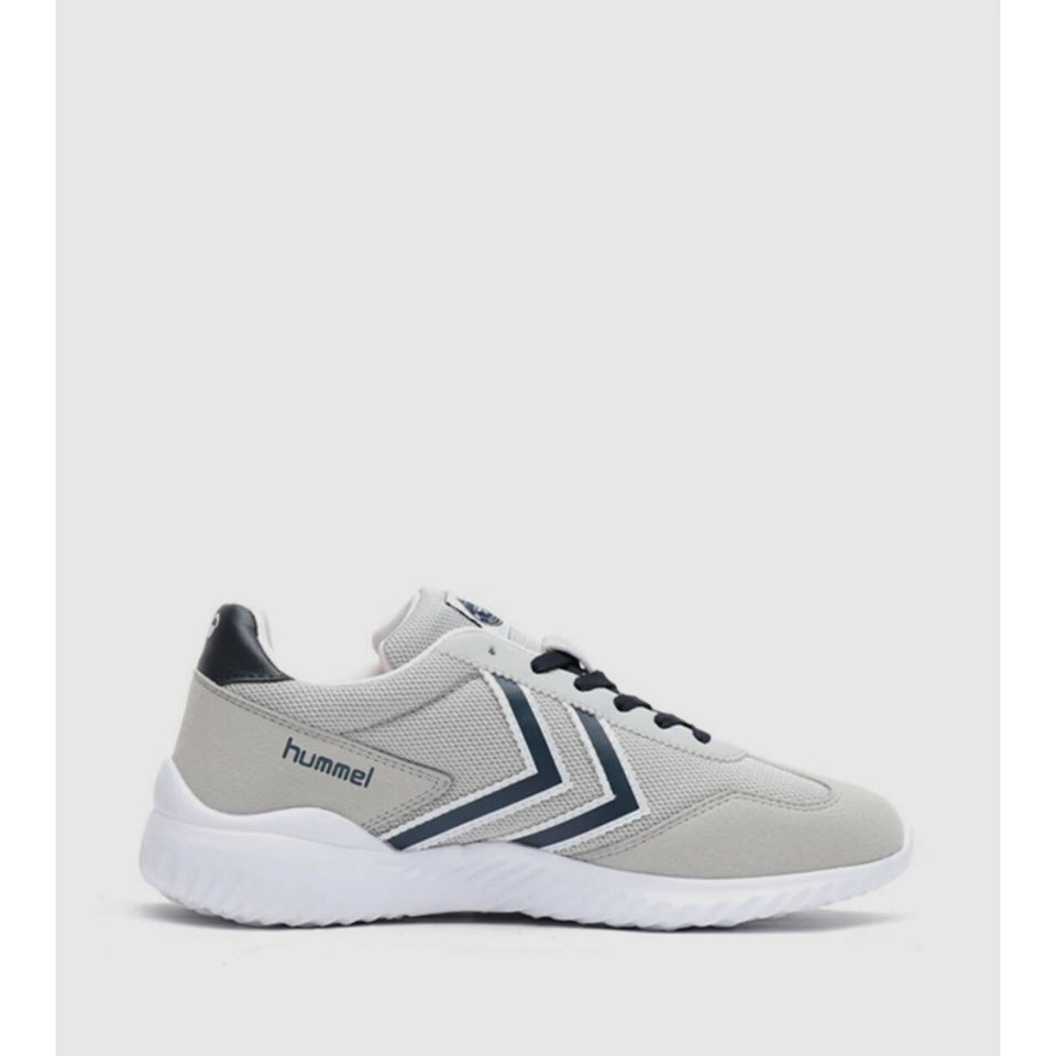 A light gray and white Hummel athletic sneaker with navy blue chevron accents and a white sole, shown from a side profile on a light gray background.