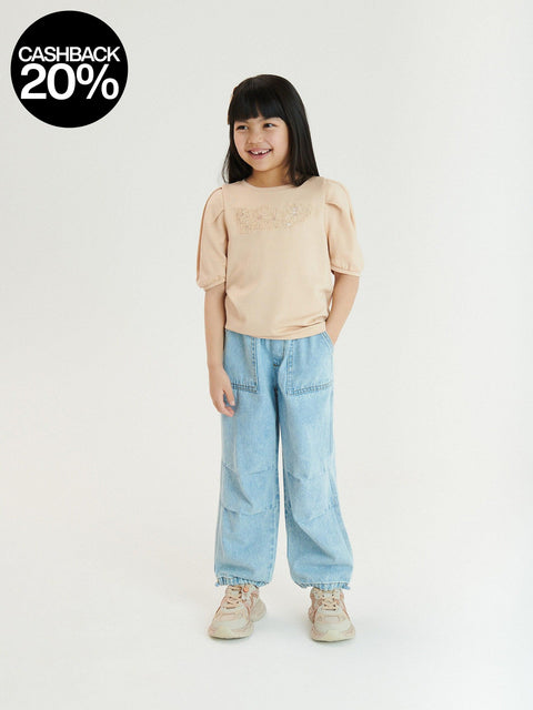 Child wearing a beige top and light blue jeans on a white background