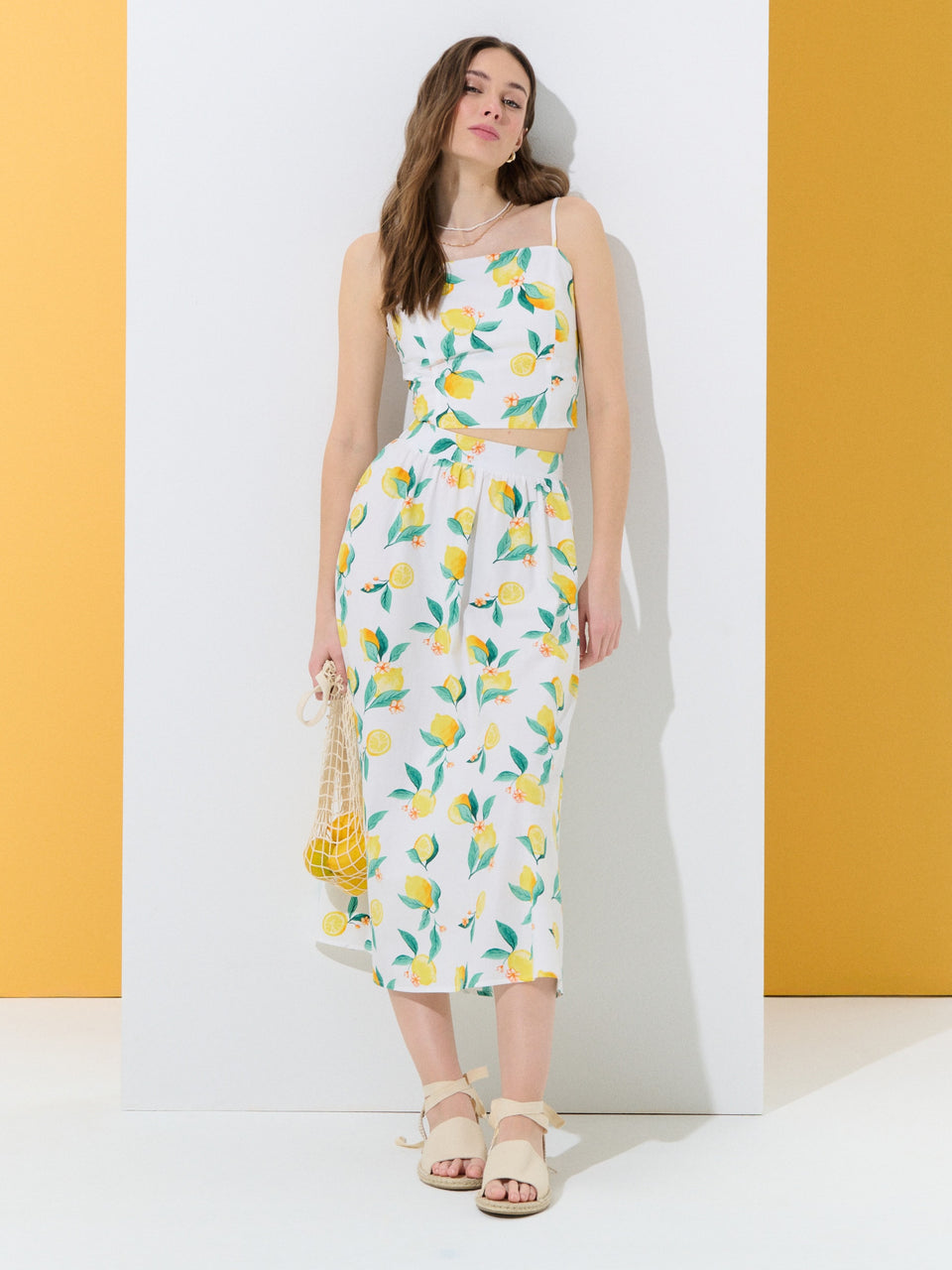 Woman wearing a floral dress with lemon pattern against a yellow and white background
